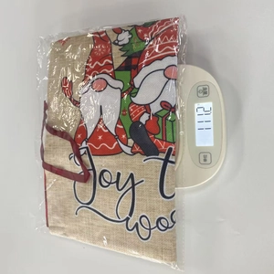Detailed view showing a Christmas gnome drawstring gift bag being weighed on a scale