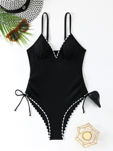 Flat lay of black V-neck swimsuit with white scalloped trim and side drawstrings