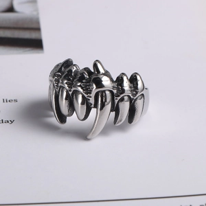 Detail of silver skull fang punk ring in titanium steel with polished finish on white background