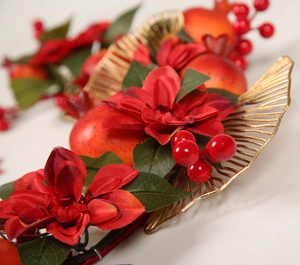 Vue détaillée d'une couronne décorative avec baies rouges, grenades et feuilles d'or
