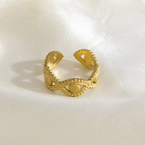 Macro view of gold stainless steel ring with evil eye pattern on white silk