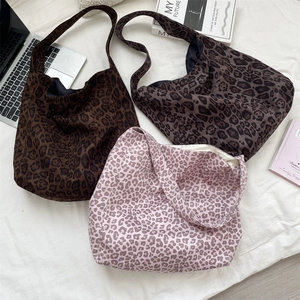 Three leopard print tote bags in brown, taupe and pink arranged on a white fabric surface