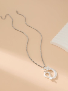 Close-up of a silver dragon pendant necklace with detailed scales and a box chain