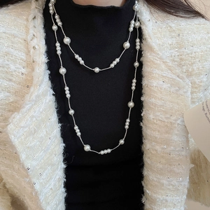 Close-up of a double-layer long pearl necklace with silver chain on a model