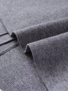 Close-up of soft grey knitted fabric texture with detailed stitching and ribbed pattern