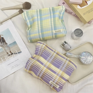 Flat lay of colorful plaid makeup bags with fabric texture and aesthetic accessories