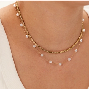 Detail of 18K gold stainless steel layered necklace with twisted chain and small white pearls
