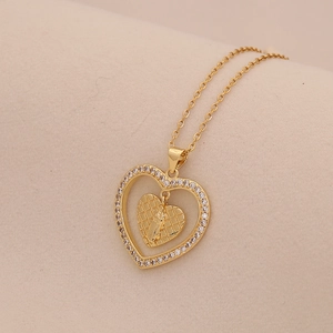 Close-up of golden double heart pendant with cubic zirconia and grid texture pattern