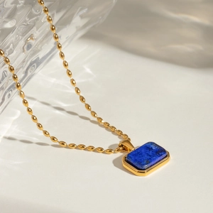 Detail of 18k gold rice chain necklace featuring a rectangular blue tiger eye gemstone
