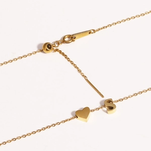 Detail of adjustable gold bolo clasp with heart and letter S pendants on a sleek chain
