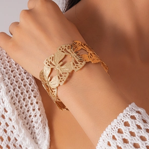 Detailed close-up of golden hollow butterfly cuff bracelet with intricate metallic texture