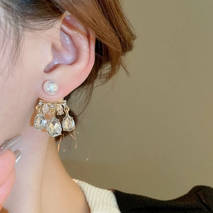 Detail of elegant pearl earrings with sparkling water drop rhinestones on a golden base