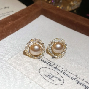 Detail of champagne pearl earrings with gold setting and small crystal inlay