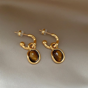 Gold plated oval tiger eye stone stud earrings with C-shaped hooks and silk background