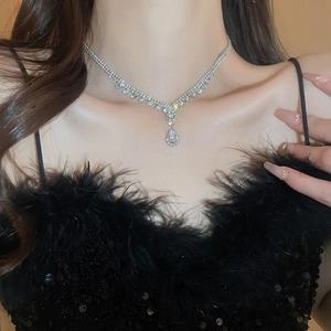 Close-up of sparkling V-shaped silver necklace with waterdrop pendant on model