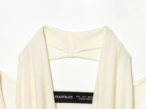 Close-up of the neckline on a cream knit top featuring the PEAOFBLRD brand label and size