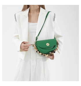 Close-up of green leather saddle bag with leopard silk scarf handle on white suit