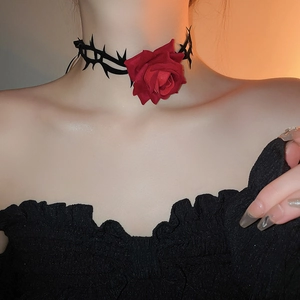 Nahaufnahme eines gotischen Halsbands mit roter Samtrose und schwarzen Dornenranken