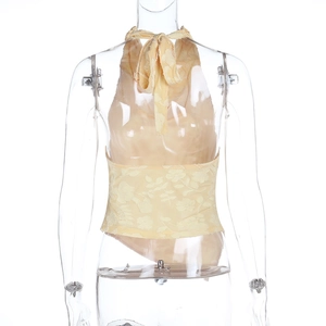 Dettaglio del top beige allacciato al collo con pizzo jacquard floreale e schiena nuda