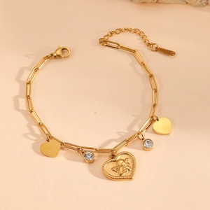 Detail of gold chain bracelet with embossed heart pendant and clear zircon charms