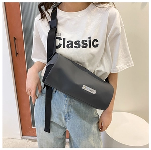 Détail du sac cylindrique gris avec bandoulière large réglable porté par un mannequin