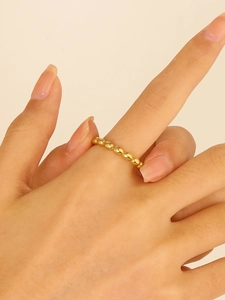 Close-up of golden beaded stainless steel ring on model finger with minimalist style