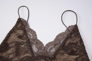 Détail du col en V en dentelle et des fines bretelles sur un caraco en dentelle marron