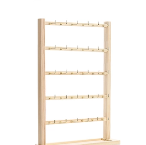 Macro detail of 5-tier wood earring stand with gold metal hooks and storage tray