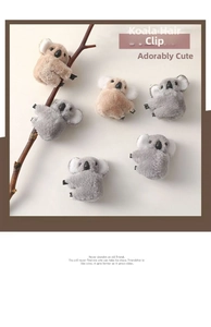 Close-up of cute plush koala hair clips in grey and brown on a natural branch
