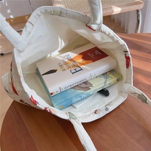 Spacious interior of white quilted tote bag holding books on a wooden table