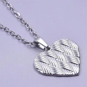 Macro view of silver heart pendant with woven texture design and polished metal finish