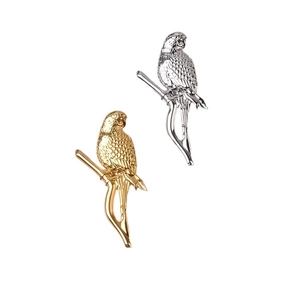 Close-up of gold and silver bird brooches showing detailed feather textures on branches