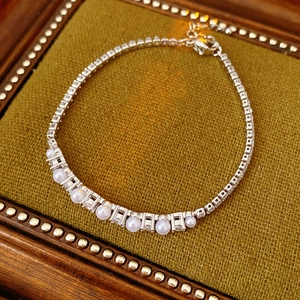 Detailed macro of zircon and pearl link bracelet on olive green velvet jewelry tray