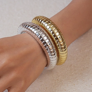 Detail of stacked gold and silver metal bangles with textured industrial ribbing