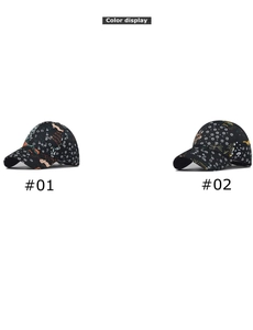 Detail view of two black baseball caps with intricate white floral and yellow bird prints
