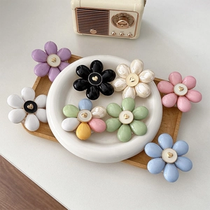 Close-up of colorful flower phone grip set with golden heart detail on wooden tray