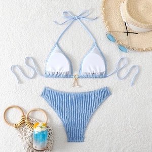 Close-up of light blue bikini with textured fabric, golden star pendant and summer props