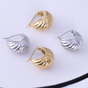 Macro detail of gold and silver chunky croissant earrings with textured metallic finish