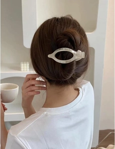 Close-up of a large beige translucent oval acrylic claw clip on woman's hair