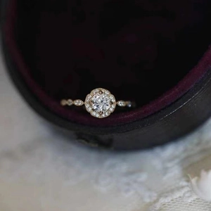 Vintage halo engagement ring with round center stone and diamond accents in gold finish