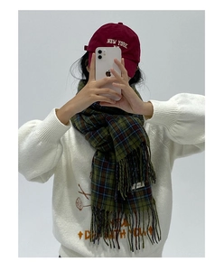 Detail shot of a soft green plaid scarf with fringe worn in a stylish autumn winter scene