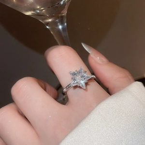 Detail of a sparkling star-shaped zircon ring worn by a model holding a glass