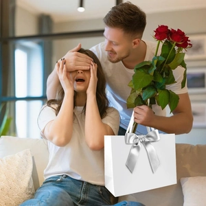 Detail of elegant white square gift bag featuring a premium silver ribbon bow
