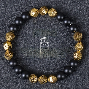 Detailed top view of black matte beads and gold faceted stones wealth bracelet on texture