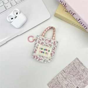 Floral fabric mini earphone case with pink lobster clasp and snap closure on white desk