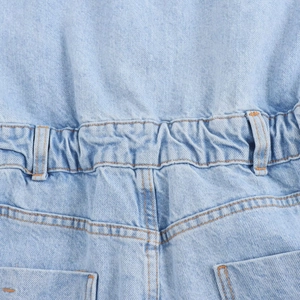 Detailed close-up of elastic waistband with orange stitching on light blue denim shorts