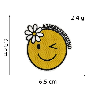 Close-up of yellow smiley face embroidery patch with Always Be Kind text and flower