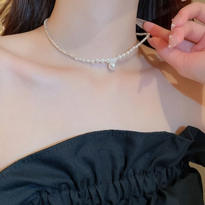 Close-up of a zircon pearl pendant necklace on a neck, showing fine silver metal textures