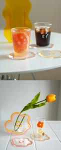 Close-up of flower-shaped acrylic coasters with colored edges and matching vase on white table