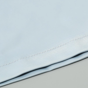 Macro shot of light blue silky fabric showing high-quality stitching and smooth texture